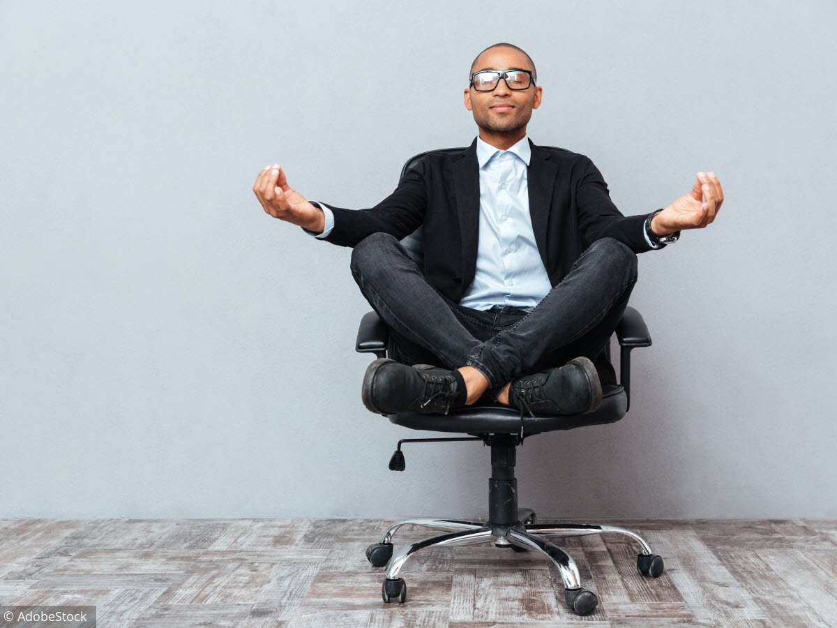 Personne assise à un bureau, écran à hauteur des yeux et pieds posés au sol