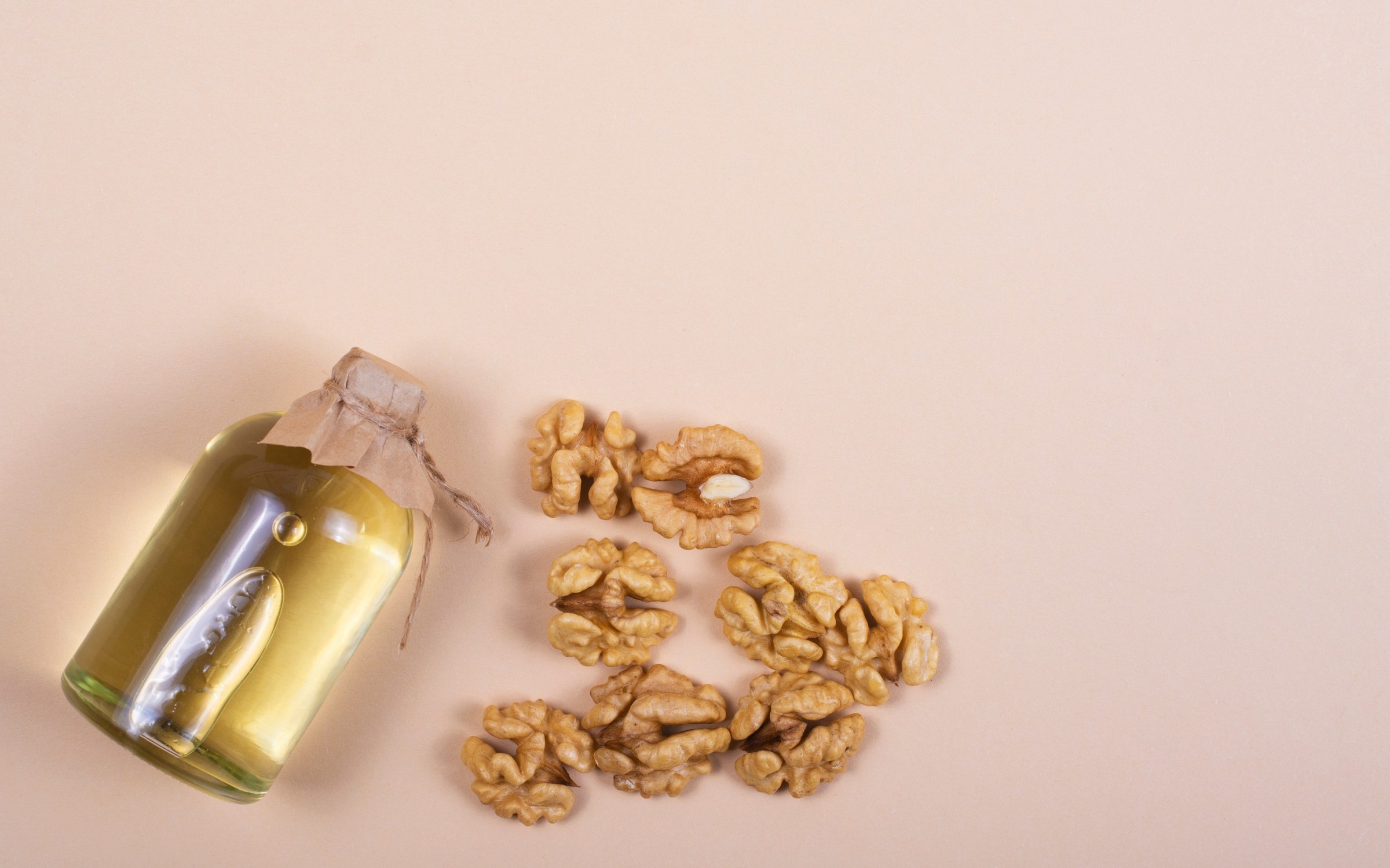 Bouteille d'huile de noix et cerneaux de noix posés sur une table en bois